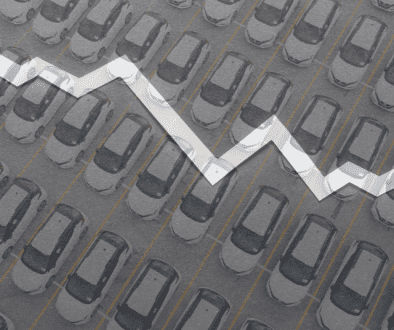 Downward trending economic arrow over a lot full of new vehicles.