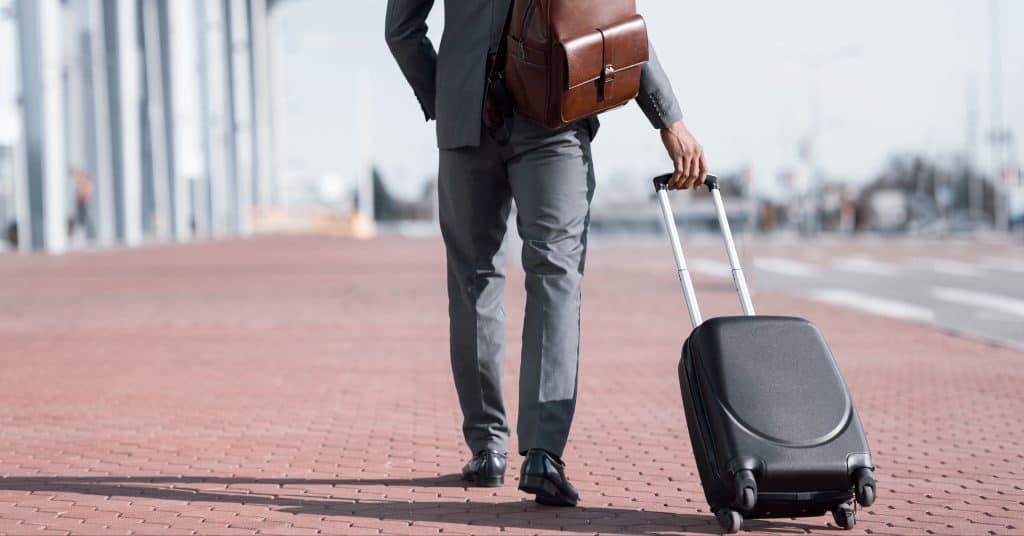 Man in suit walking with luggage.