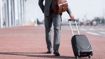 Man in suit walking with luggage.