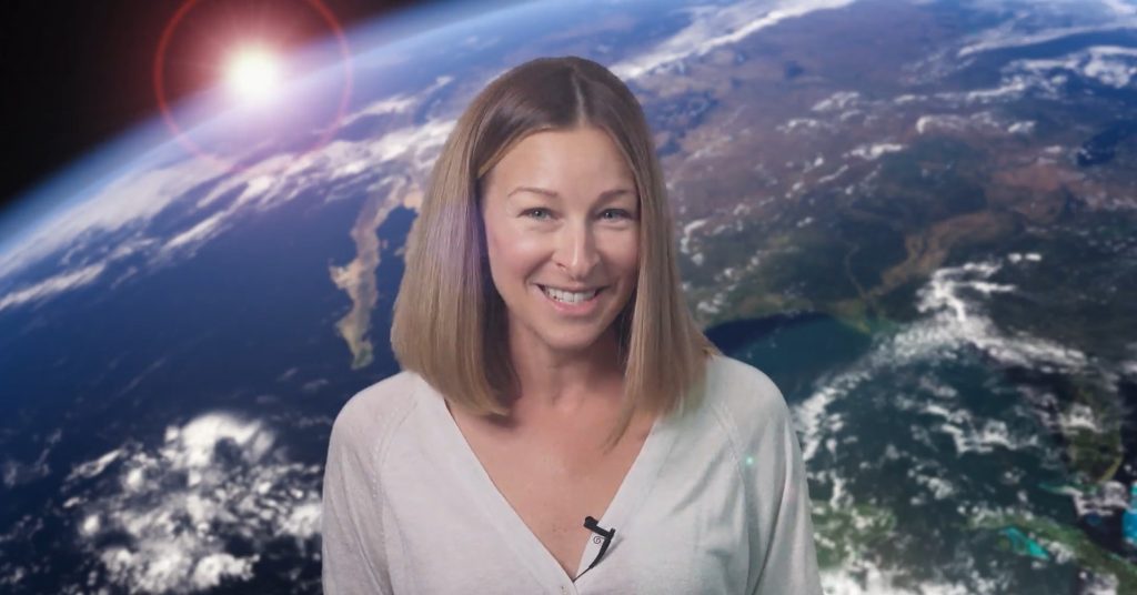 a woman smiles in front of a virtual background, which is a view of Earth from outer space